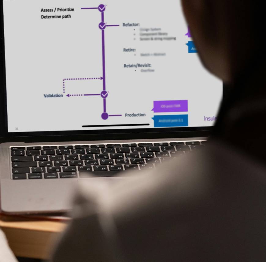 Individual at a desk, focused on a laptop screen displaying the process of migrating design assets between two major design platforms